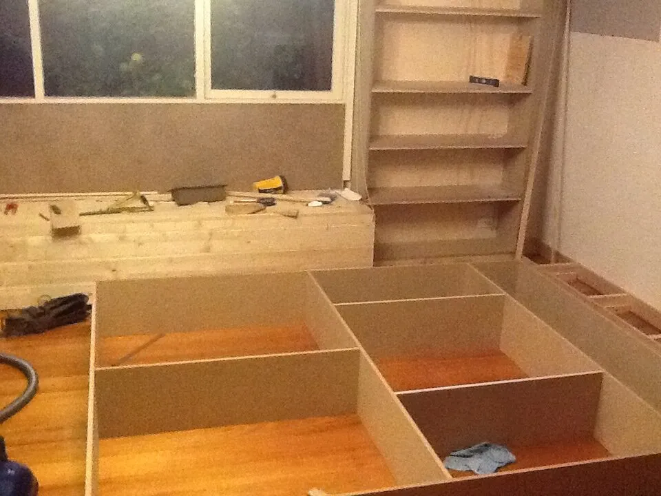 Window seat carcasses and a tall bookcase set out in the room before the fronts went on.