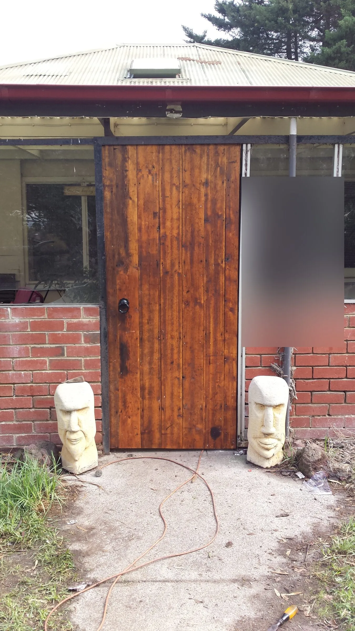 A solid timber door hung in a brick entry, with the porch screening either side of it.