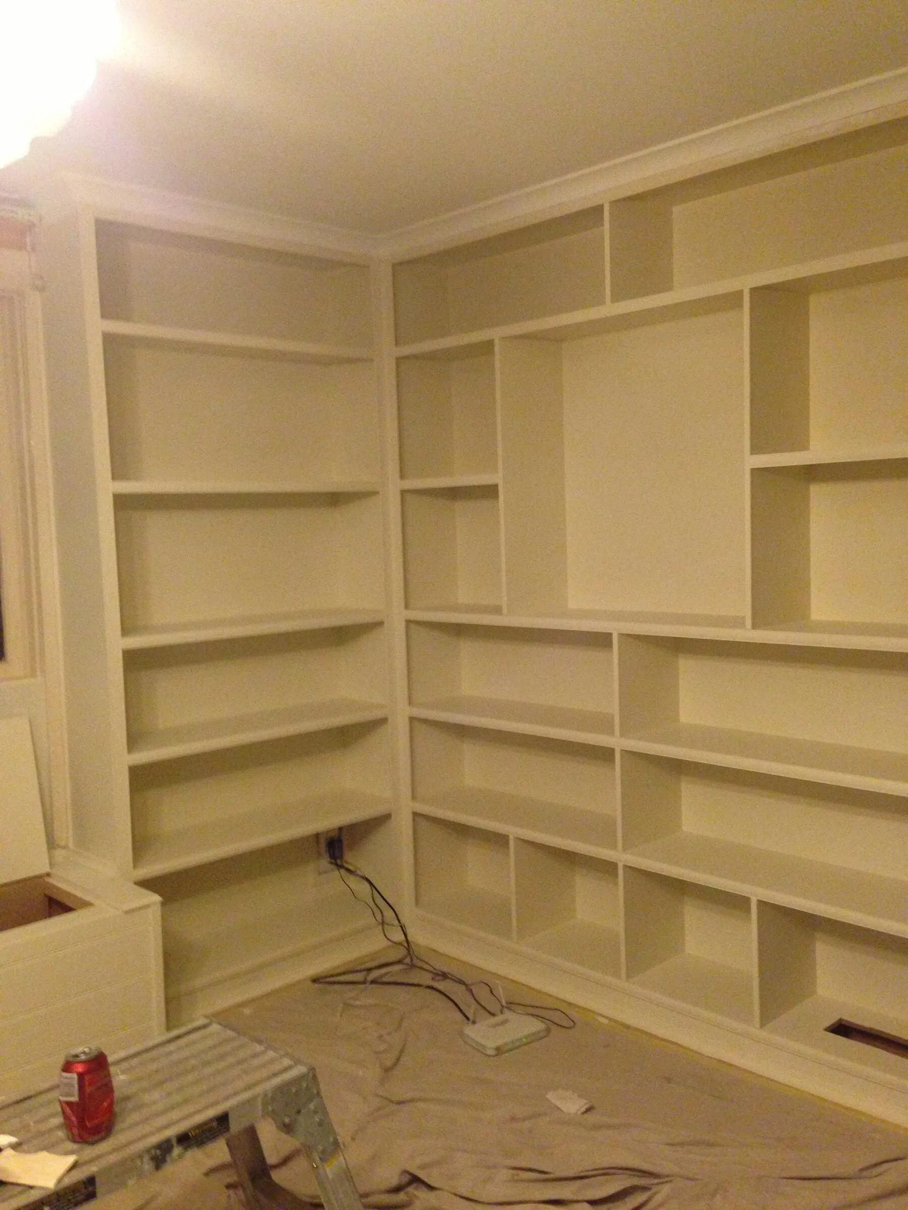 Built-in bookshelves run around two walls of a study, painted and ready for the skirting.
