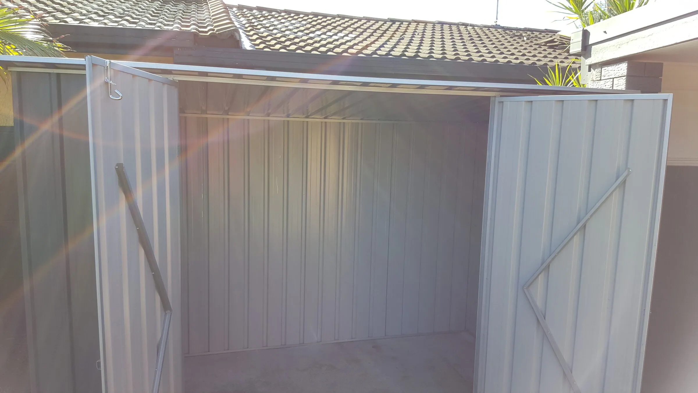 The same enclosure with both doors open, showing the lined interior and the braced doors.