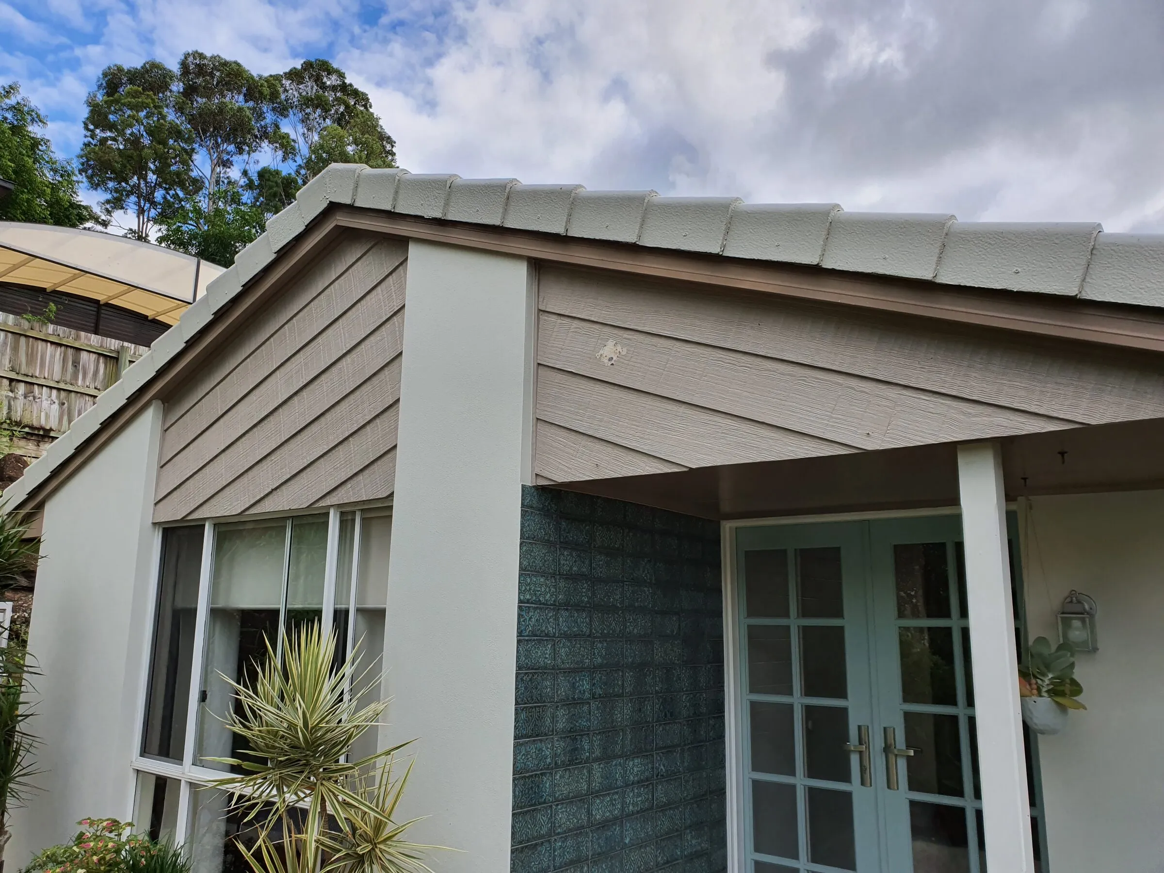 The gable end before the work, the old painted boards weathered and splitting.