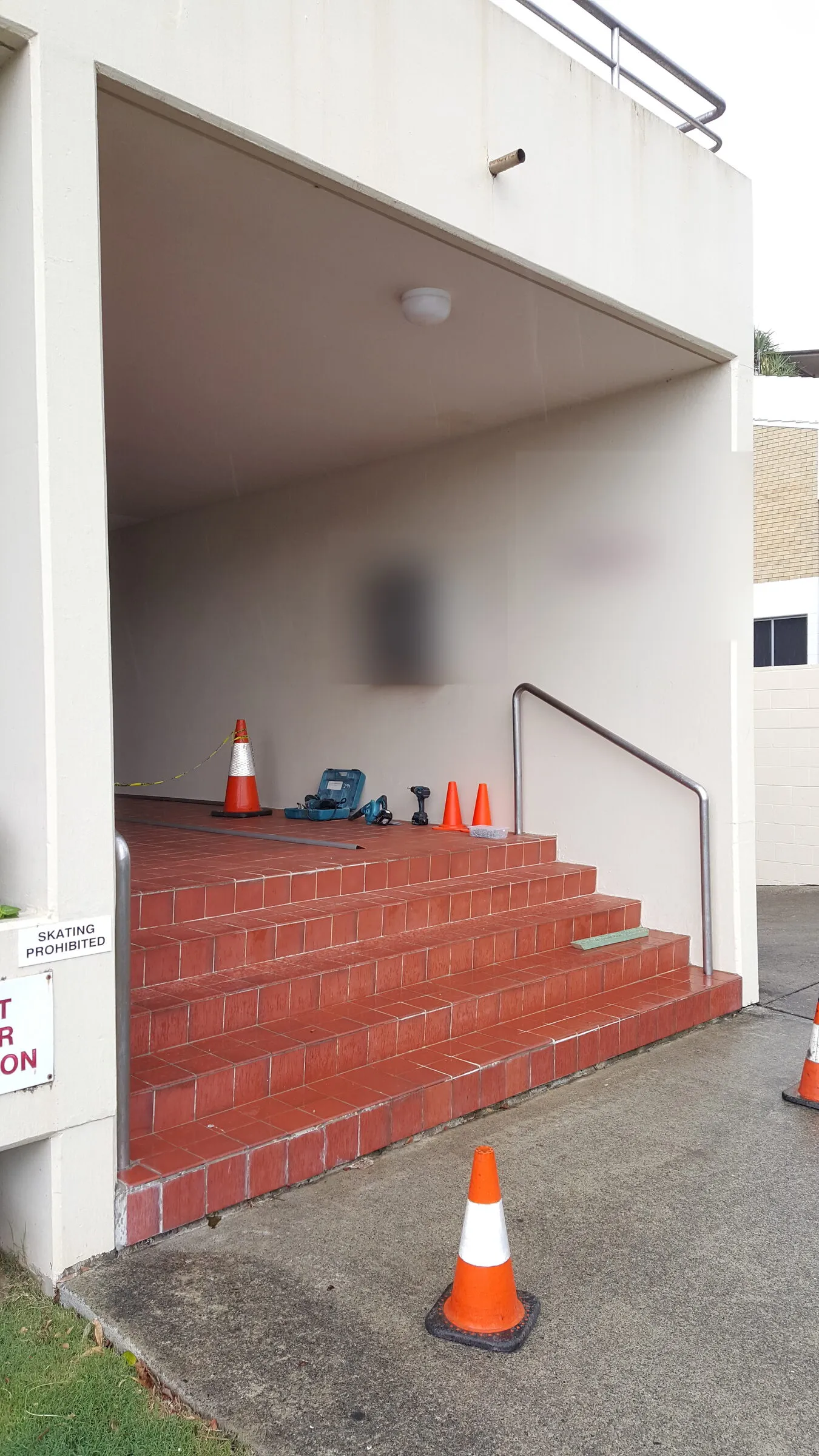 Tiled entry stairs to a unit block with the first stainless handrail up and cones out while the second side is fitted.