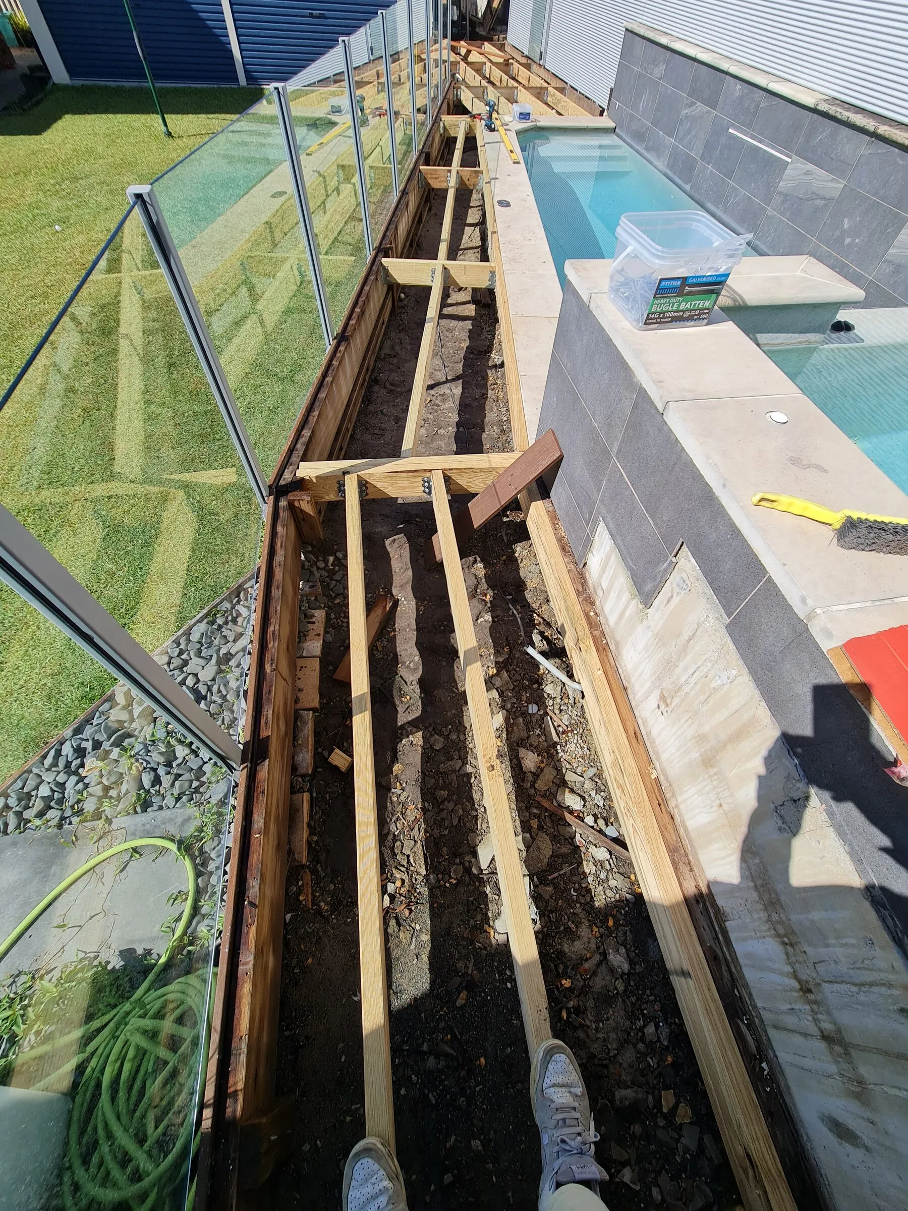 Fresh joists set into the trench beside the pool, the old rotted timbers cut out and carted off.