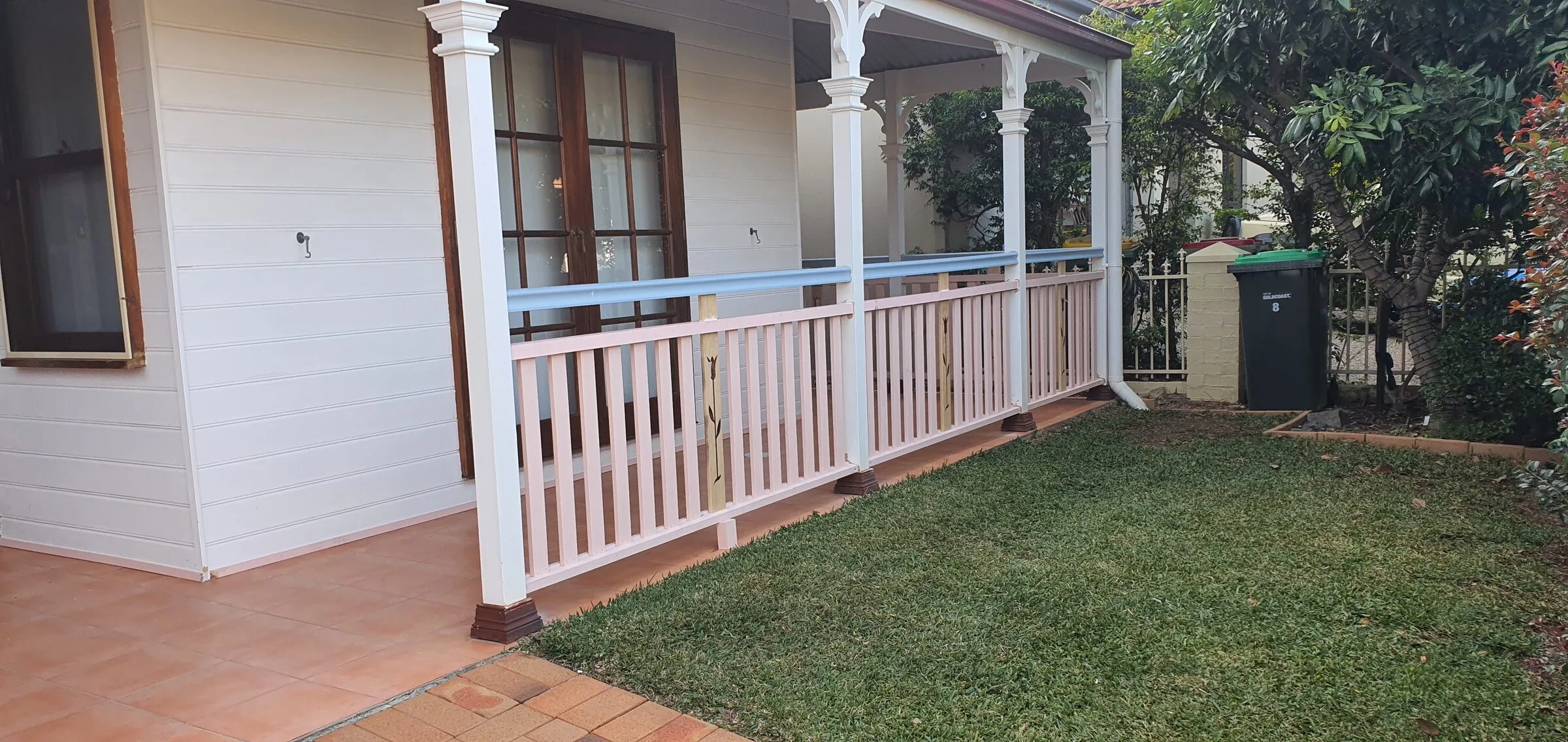 New white balusters and rails going in between the turned posts along the front of the cottage.