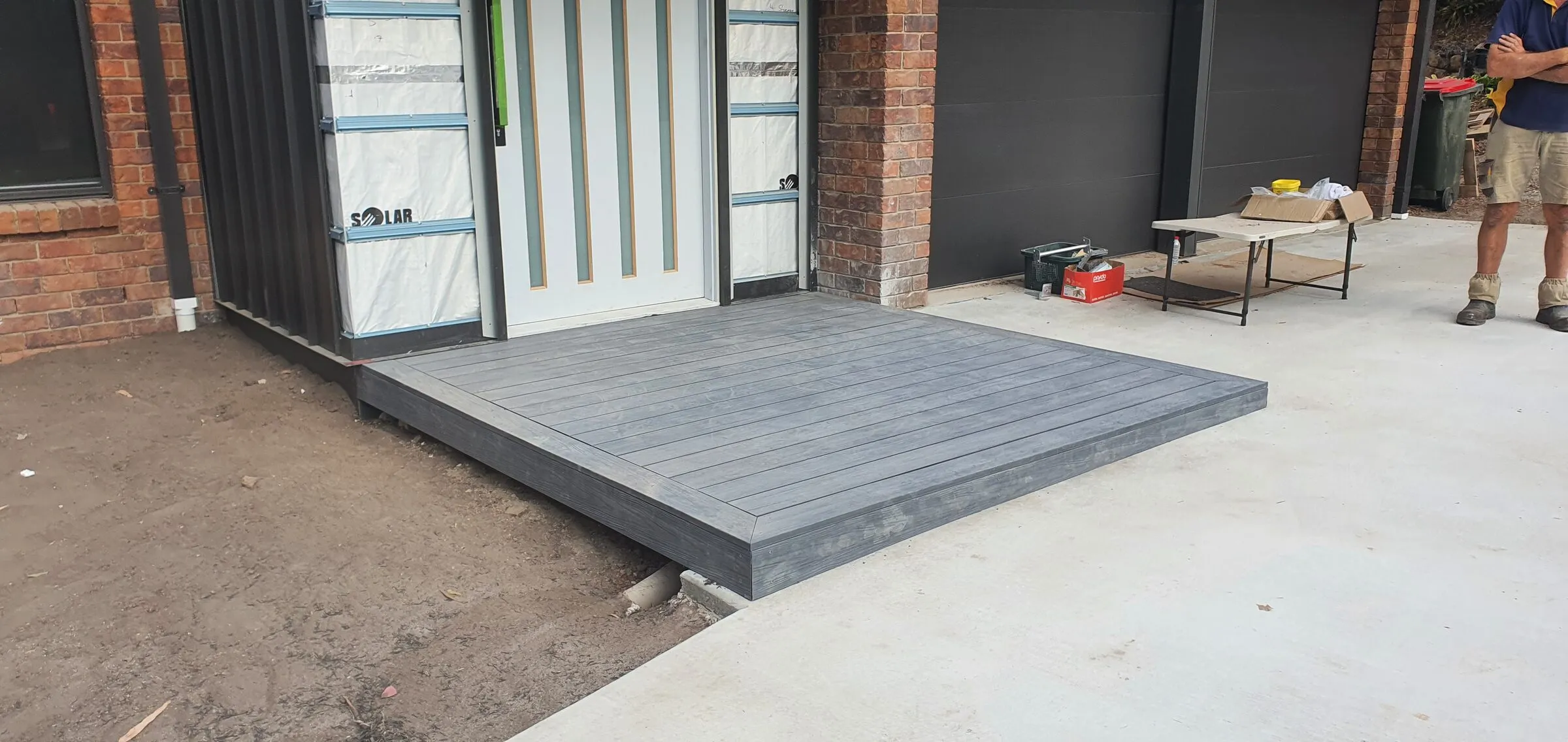 A low composite-board landing laid at the entry doors, boards run square and finished flush with the concrete.