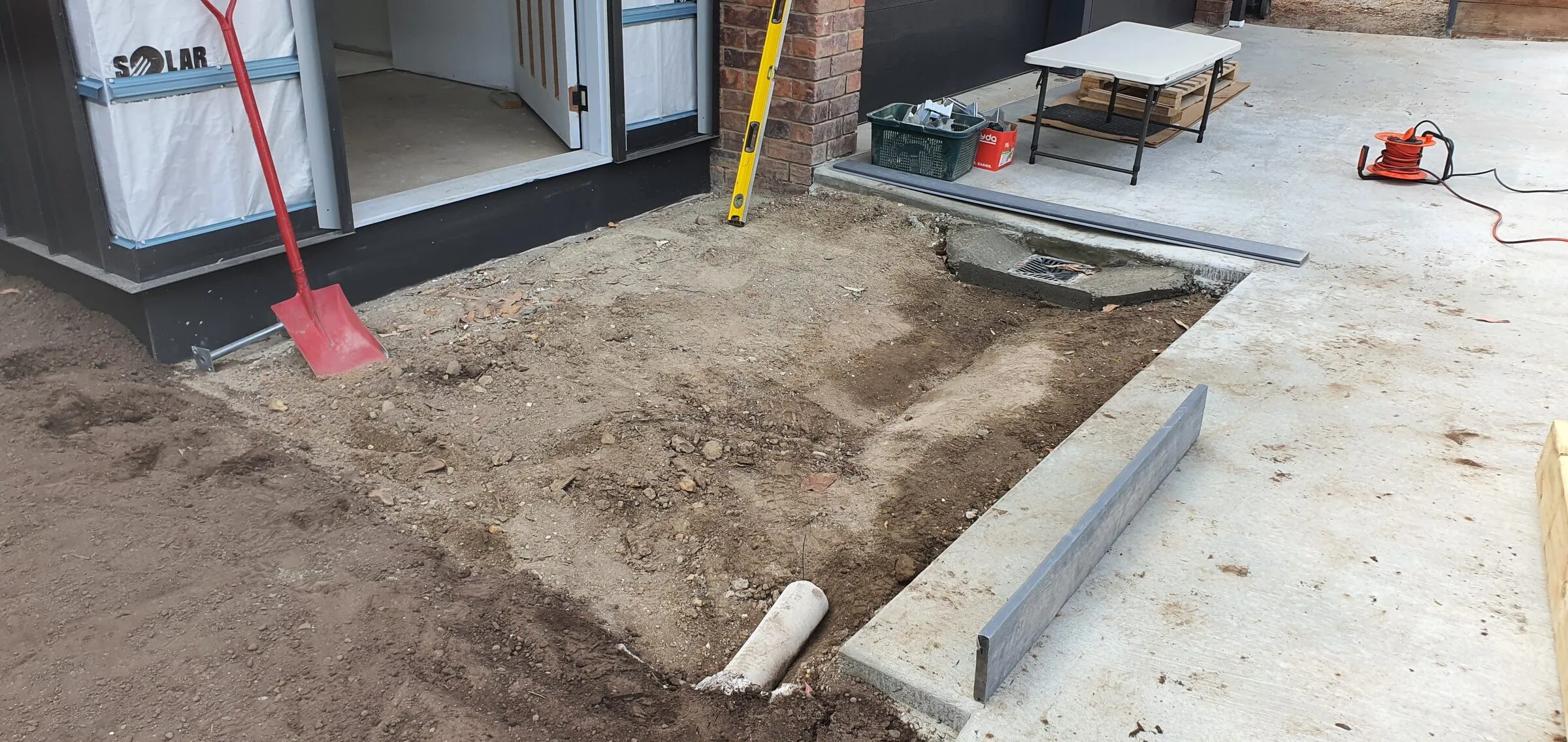 Bare ground and the edge of the slab at the entry to a container home before the composite boards went down.