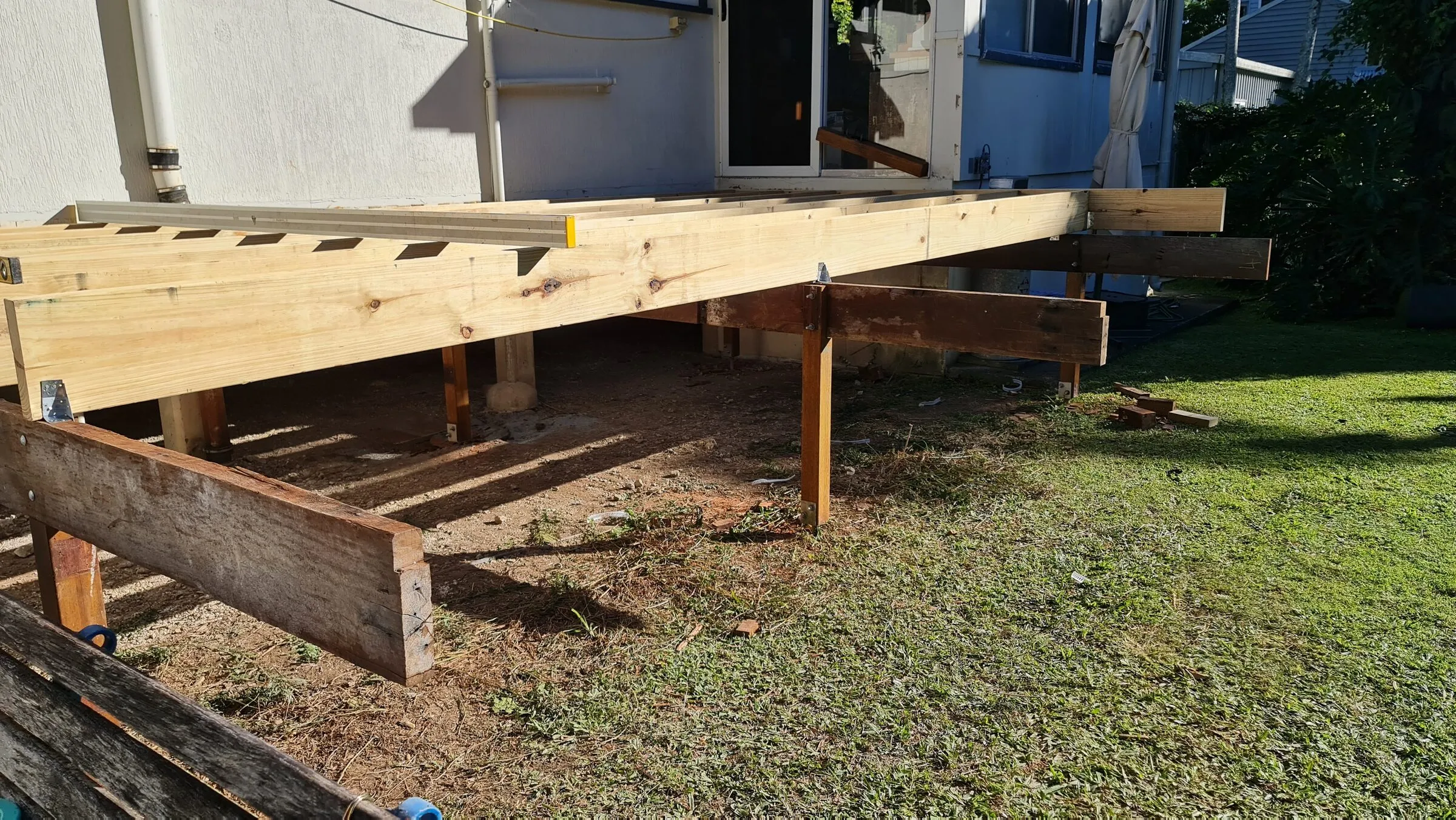 New posts and bearers carrying the subfloor out from the wall to the lawn.